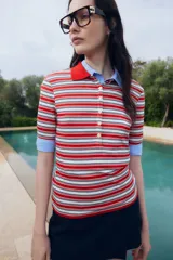 Remera polo de punto acanalado a rayas rojas, blancas y azul marino, con cuello rojo y tapeta de botones.