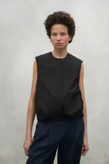Chaleco negro sin mangas con cuello redondo y cierre frontal con botones. Corte holgado y largo a la cadera.