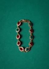 Pulsera dorada con eslabones de bronce y cristales rojos, verdes y blancos engarzados en forma floral.
