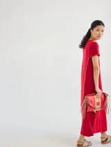 Vestido largo rojo de tejido de punto, con cuello en V y mangas cortas. Presenta costuras verticales a lo largo del vestido.