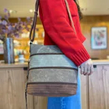 Bandolera marrón con paneles combinados en tonos beige y verde. Tiene apertura superior con cierre, bolsillo frontal con cierre, tres bolsillos internos (dos con cierre), bolsillo trasero con cierre y correa larga regulable.