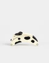 Broche para el pelo con forma de perro de color crema con manchas negras.