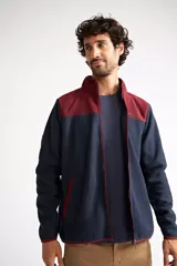 Campera polar para hombre, color azul marino con canesú y cuello en color borgoña. Tiene cierre frontal completo, bolsillos laterales con cierre, puños y ruedo elastizados, y logo estampado en el pecho.