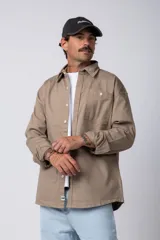 Camisa verde militar de manga larga, corte oversize, con cuello clásico, cierre frontal con botones y bolsillo en el pecho. Confeccionada en algodón suave y con costuras a la vista.