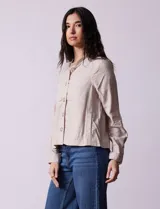 Chaqueta color beige de lino y rayón, con cuello mao, cierre frontal con botones y bolsillos delanteros.