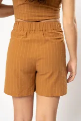 Short color ocre con finas rayas verticales blancas, tiro alto, bolsillos laterales y botón de madera.