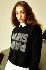 Buzo negro de corte clásico con cuello redondo y puños y cintura acanalados. Estampado frontal con la palabra "Paris" en letras blancas con efecto 3D.