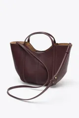 Bolso mini city color borgoña, con asa de mano y asa bandolera extraíble. Tiene detalle de pespuntes en contraste y bolsa interior extraíble con cierre de cremallera.