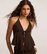 Blusa marrón oscuro con textura plisada, estilo frente única (halter) con escote en V profundo y lazo ajustable en el centro del busto. Presenta un ruedo con volado o efecto nube.