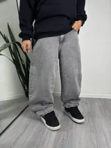 Pantalón baggy gris con bolsillos laterales y traseros. Estampado con la palabra "Gangster" en el bolsillo trasero.