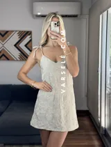 Vestido corto marrón con estampado de flores blancas, escote en V y tirantes finos.