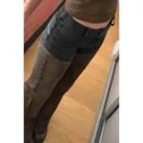 Pantalón de cuero negro y marrón con corte texano y flecos en el lateral.