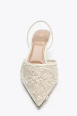 Zapato destalonado color blanco hueso, con tacón fino y punta fina. Capellada de mesh con bordados florales.