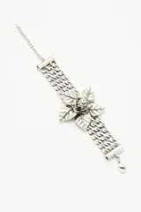 Pulsera metálica plateada con cadenas de eslabones gruesos y flor central con textura y detalles de strass.