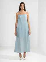 Vestido largo hasta el tobillo color celeste, de tejido arrugado y liviano. Presenta un escote recto con finos breteles, lazos delicados en los costados y un forro que llega hasta arriba de las rodillas.