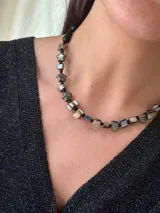 Collar corto con cuentas de nácar con subtono negro, mostacillas y cristales checos. Se cierra con cadena de acero quirúrgico y ganchito para regular el largo.