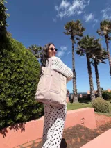 Bolso tipo shopper de color rojo con doble asa de mano y correa larga ajustable y extraíble. Presenta un diseño funcional con un bolsillo frontal abierto y gran capacidad interna.