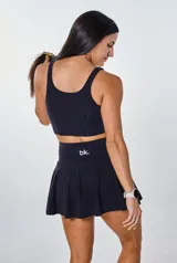 Conjunto deportivo negro compuesto por un top con logo "bk." y una falda corta con short interno.