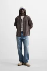 Camisa de hombre color gris con diseño a cuadros, corte relaxed fit, cuello bowling, manga corta y cierre frontal con botones.
