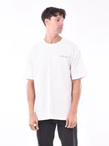 Remera blanca de corte oversized con logo pequeño estampado en el pecho.