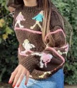 Sweater marrón tejido a mano con diseño de personas corriendo en colores rosa, celeste, blanco y amarillo. De corte holgado y cuello redondo.