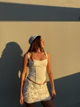 Conjunto de top corset con breteles finos y falda mini con lentejuelas, ambos color blanco.