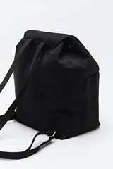 Mochila negra de símil gamuza con textura tipo reptil, diseño minimalista con solapa, cordón ajustable y bolsillos laterales.
