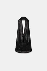 Top halter de tul color gris claro, con escote fluido drapeado y espalda descubierta. Presenta bordados con aplicación de abalorios en tonos oscuros y dorados.