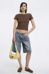 Cartera de hombro amarilla con tachas y dijes de cerezas.