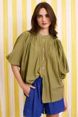 Camisa verde militar de algodón con mangas murciélago, corte holgado y botones florales azules.