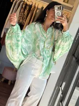 Camisa celeste con estampado abstracto, de corte amplio, cuello camisero y mangas largas abullonadas con puños elásticos.