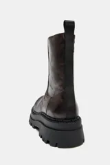 Botín de estilo urbano con efecto desgastado, confeccionado con suela de plataforma dentada y puntera redonda. Cuenta con un diseño tipo pull-on y tirador trasero para facilitar el calce.