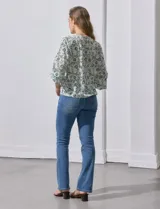 Blusa de gasa color blanco con estampado de hojas verdes, de mangas 3/4 abullonadas con puños elásticos.