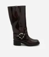 Bota biker de caña alta color marrón oscuro, con puntera redonda, taco bajo y detalle de hebilla con aro metálico en el lateral.