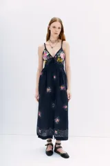 Vestido midi negro con estampado floral, escote en V, breteles finos cruzados en la espalda, cintura con lazo y falda con vuelo.