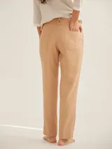 Pantalón cigarette color beige, de corte recto y tiro medio, con bolsillos laterales y cierre frontal con botón y cremallera.