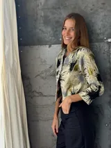 Blazer corto con estampado abstracto en tonos dorados, negros y grises. Tiene mangas 3/4 y corte recto.