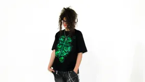 Remera negra de corte regular fit, confeccionada en jersey de algodón grueso. Estampa frontal con diseño de cruz y calaveras en color verde.