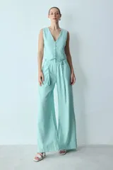 Chaleco blanco con escote en V, corte entallado, botones forrados y hebilla ajustable en la espalda.