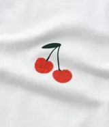 Blusa blanca de algodón con cuello redondo, manga corta abullonada y estampado de cerezas.
