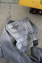 Pantalón de jean recto color gris oscuro, de tiro medio, con costuras verticales y bordado de brújula en los bolsillos traseros.