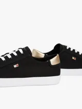 Zapatillas Tommy Hilfiger de lona negra con suela blanca de goma y talón dorado metalizado.