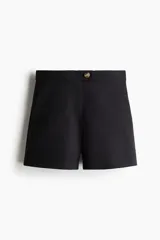 Short negro de tiro alto con cierre y pretina prolongada con botón. Modelo con bolsillos al bies y bolsillos insertados decorativos atrás.