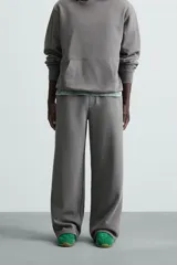 Pantalón jogger wide fit negro confeccionado en tejido de algodón con interior rizo. Pernera ancha, cintura elástica ajustable con cordón interior, bolsillos laterales y bolsillo trasero de plastrón.