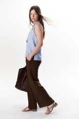 Top sin mangas color terracota con cuello redondo y bolsillo frontal. Presenta costuras a contratono en blanco que definen los bordes y el bolsillo.