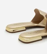 Sandalia plana de mujer color blanco hueso, con tira única ancha y puntera cuadrada abierta. Posee un taco bajo y suela de goma marrón.