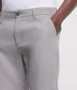 Bermuda de hombre color gris claro, corte slim, con trabillas en la cintura, cierre con botón y cremallera, lazo interno, bolsillos delanteros y traseros, y tejido texturizado.