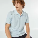 Remera polo celeste de piqué de algodón con estampado de pequeñas líneas verticales negras.