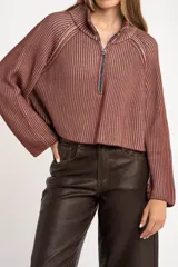 Sweater de punto morado con cierre metálico parcial en el cuello alto y mangas largas.