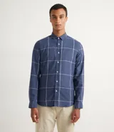 Camisa de franela azul con estampado de cuadros blancos y beige, de manga larga y cuello camisero.
